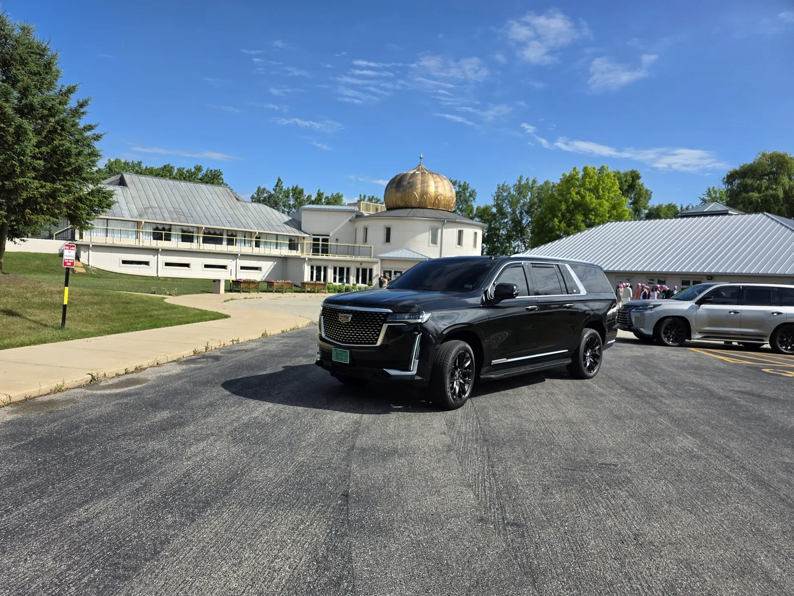 Black Cadillac Escalade parked in front of a white hall with a gold onion dome