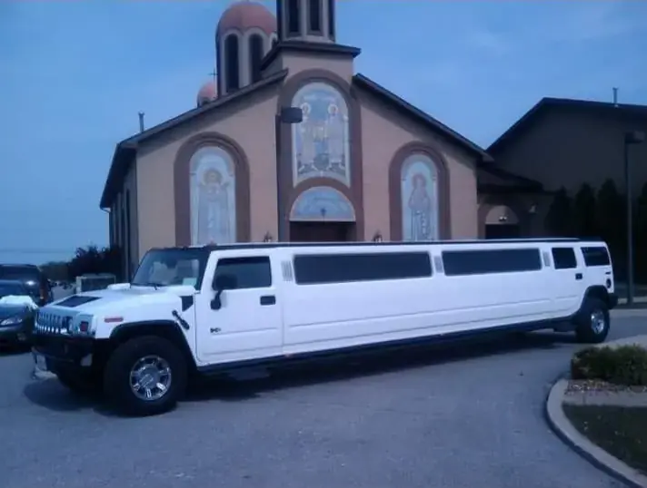 White Hummer stretch limousine parked outside an Orthodox church at dusk