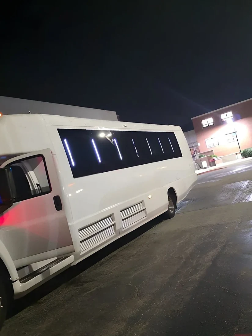White 34-passenger party bus with lit windows at night