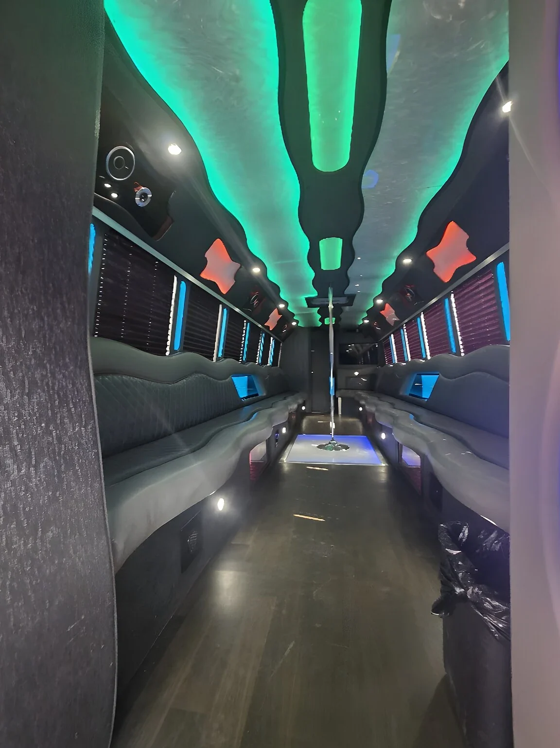 Party bus interior with wraparound seating under green LED lighting