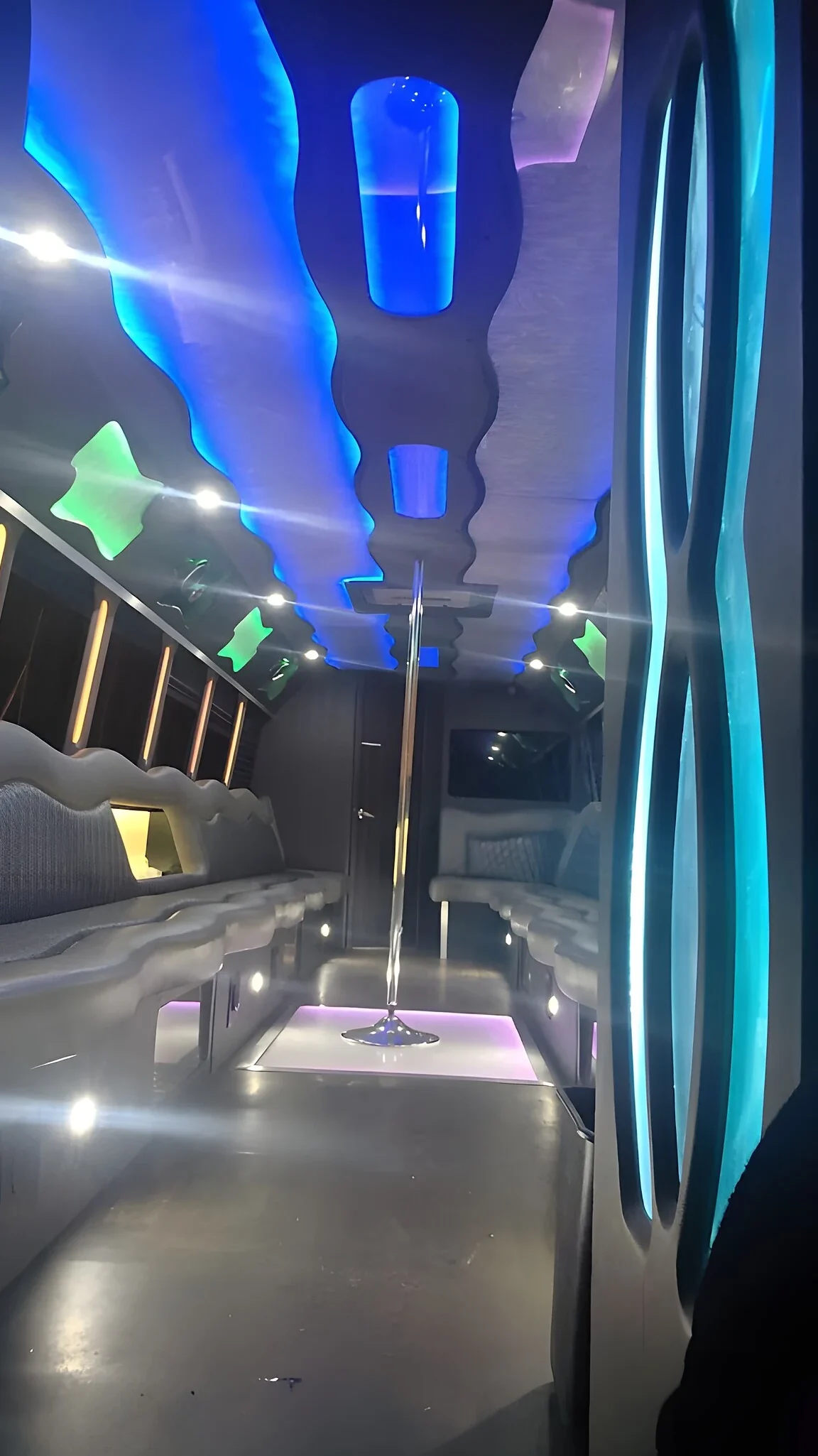Party bus interior with a dance pole under blue LED lighting
