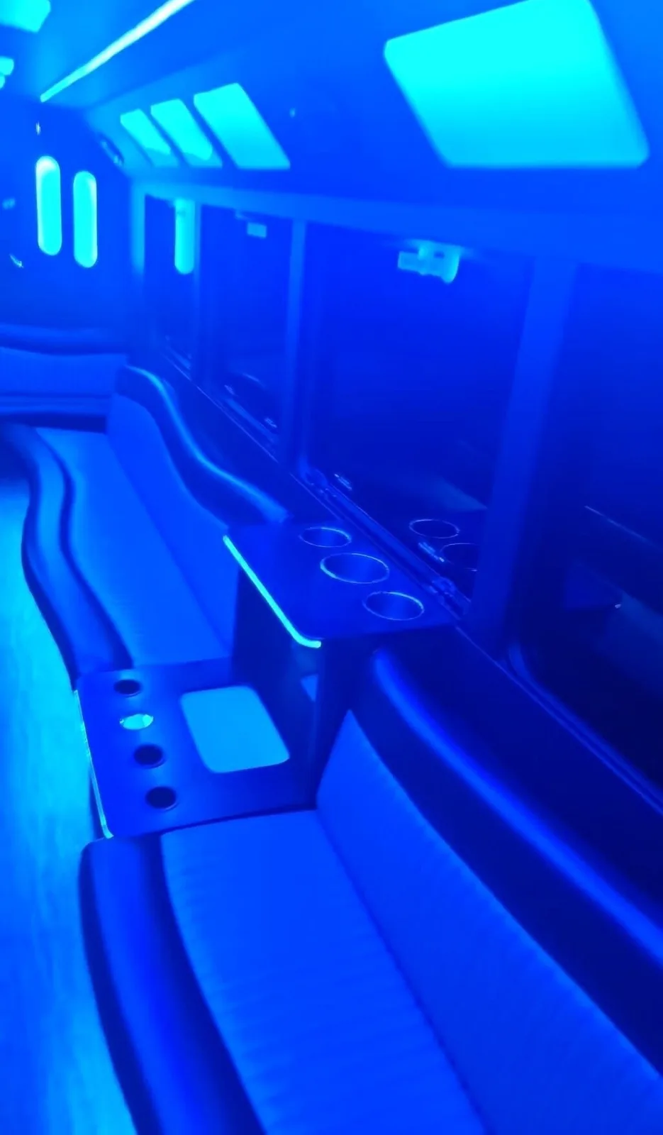 Party bus interior washed in blue LED light with wraparound seating
