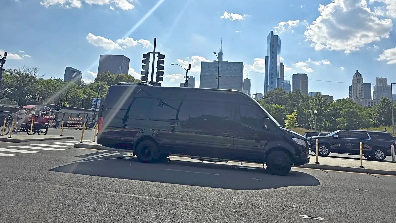 Black Mercedes Sprinter parked at a downtown Chicago intersection with the skyline behind it