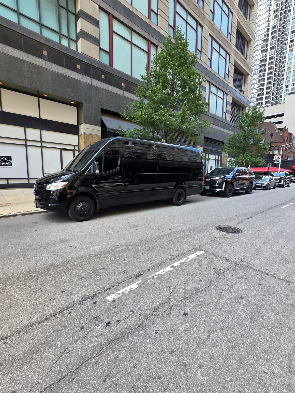 Black Mercedes Sprinter parked on a downtown Chicago street beside a high-rise