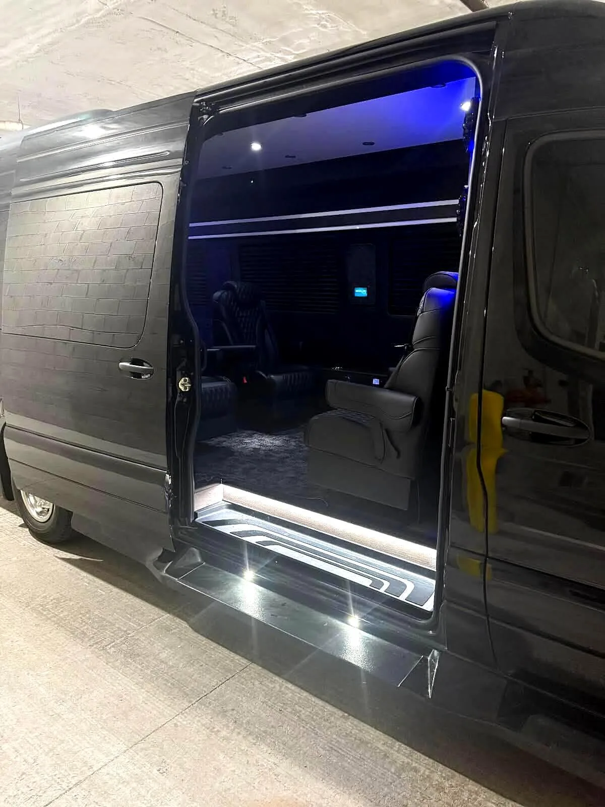 Black Mercedes Sprinter with its sliding door open and step lights on