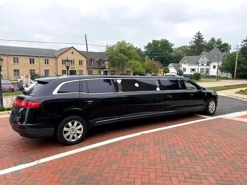 Black Lincoln stretch limousine at the curb on a brick street
